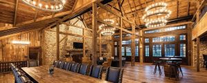 Luxury oak farm home with wood beams, chandeliers, long dining table and black chairs
