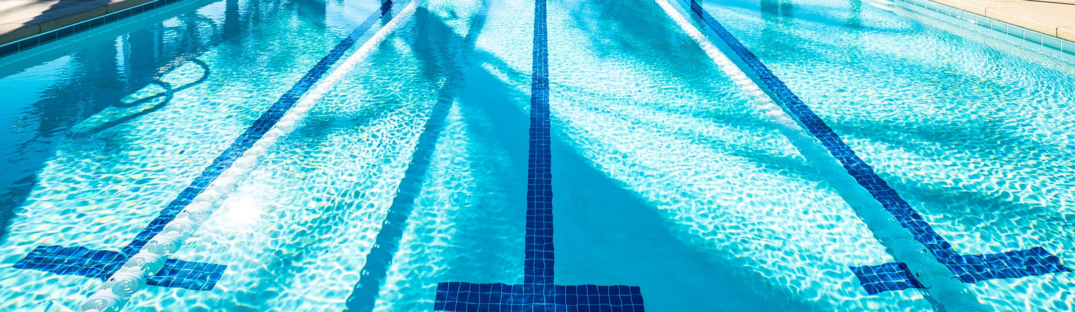 View of pool with 3 lanes and blue tiles that create 3 T shapes on the bottom.