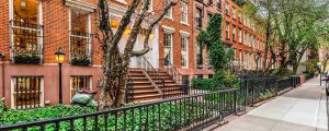 Brownstone with red bricks, trees, stairs, rod iron railing and bushes