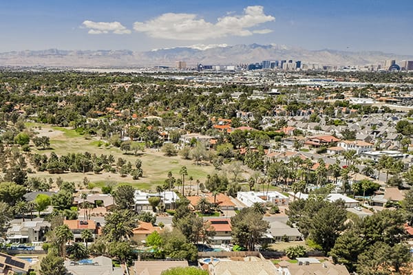 Aereal shot of golf course, trees, homes and high rise skyline