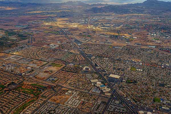 High areal shot of desert city with homes, trees, streets and freeways.