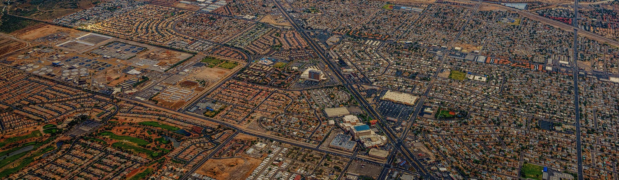 High aerial view of city with houses, trees, streets and freeways