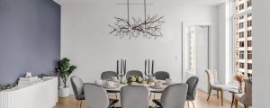 Large gray dinning table with gray chairs ad chandelier