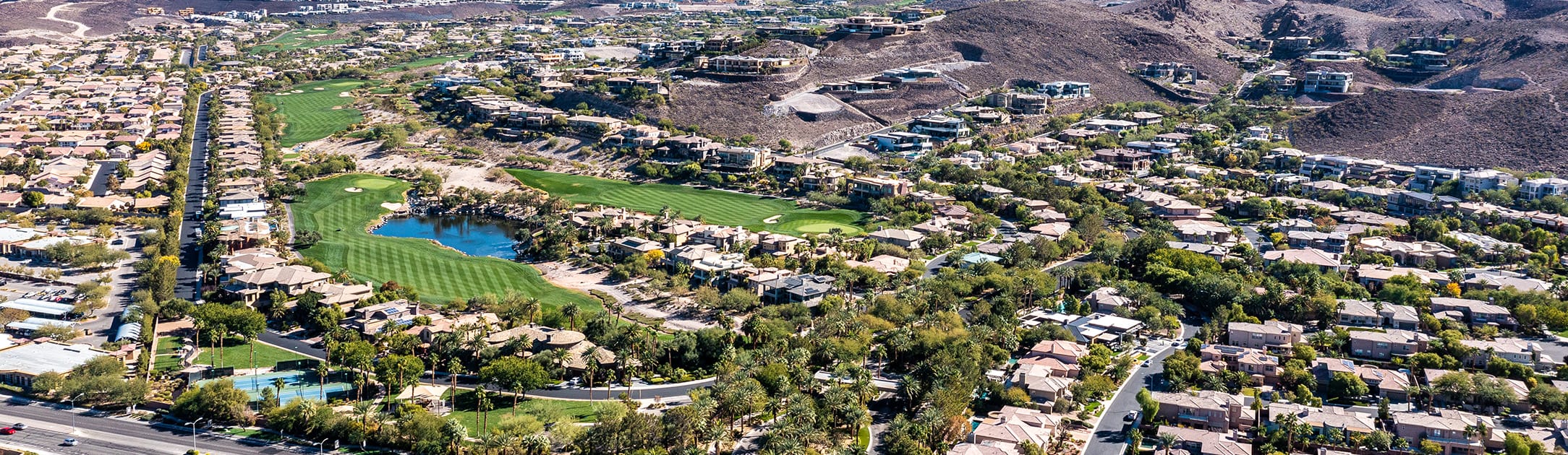 Aerial view of golf course with luxury homes that go up a hillside.