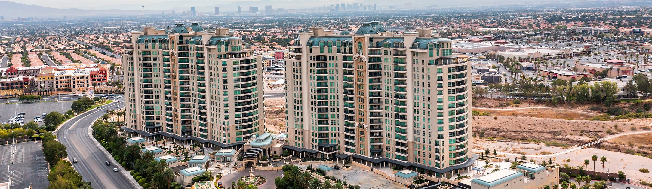 2 high rises with an outdoor shopping center and homes around it.