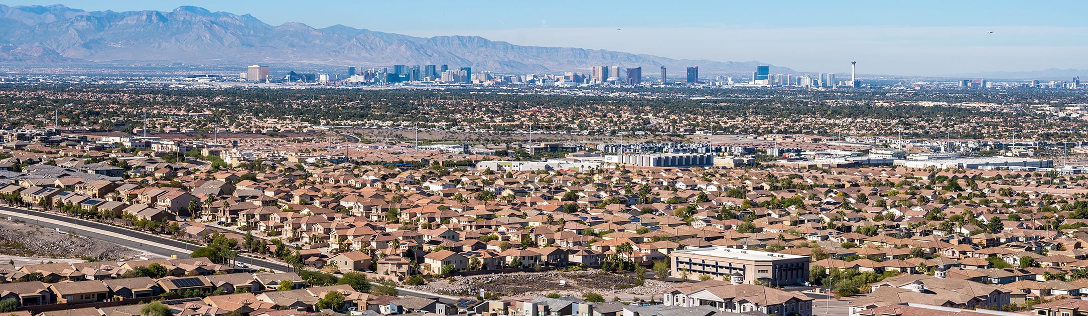 Aerial view of neighborhood with high rises and mountains in the background.