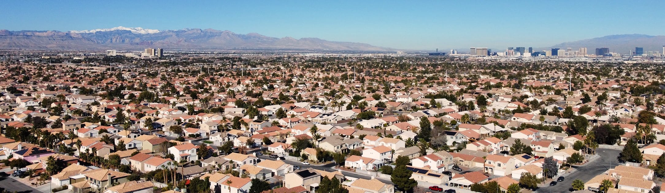 Aerial view of neighborhood with high rises and mountains in the background.