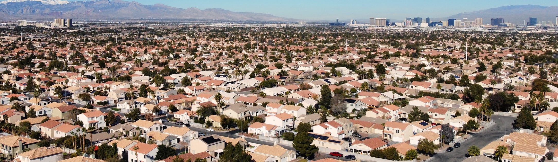Aerial view of neighborhood with high rises and mountains in the background.