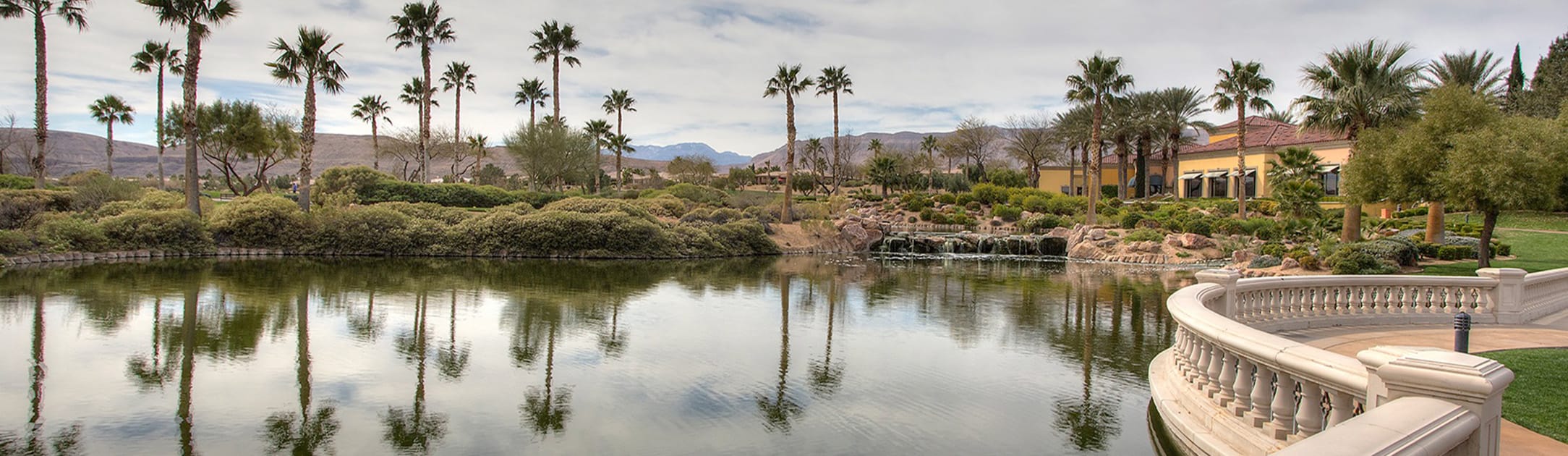 Lake, bushes, palm trees with mountains in the background.
