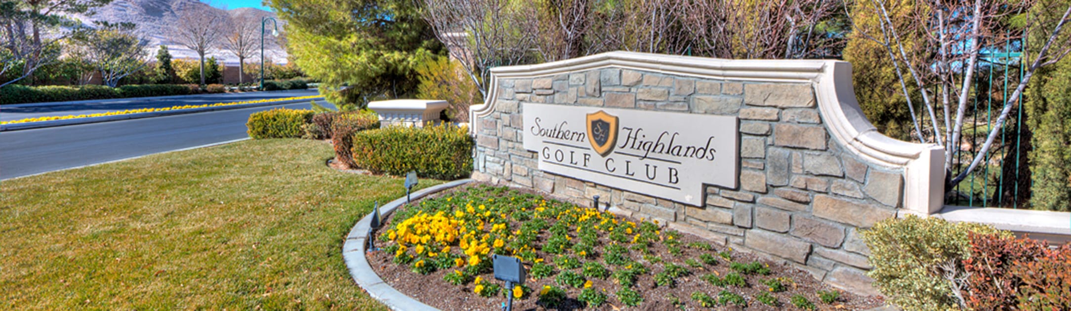 Brick stand with sign that says Southern Highlands Golf Club, bushes, trees and flowers.