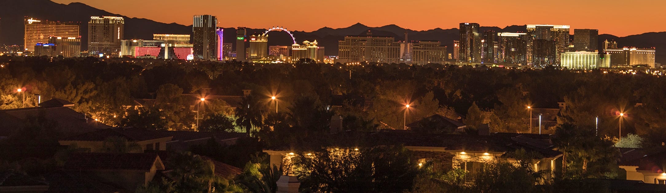 Twilight view of neighborhood with high rises and casinos in the background and orange sunset.