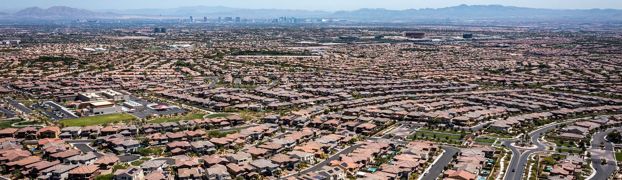 Aerial view of neighborhood with high rise skyline and mountains in the background.