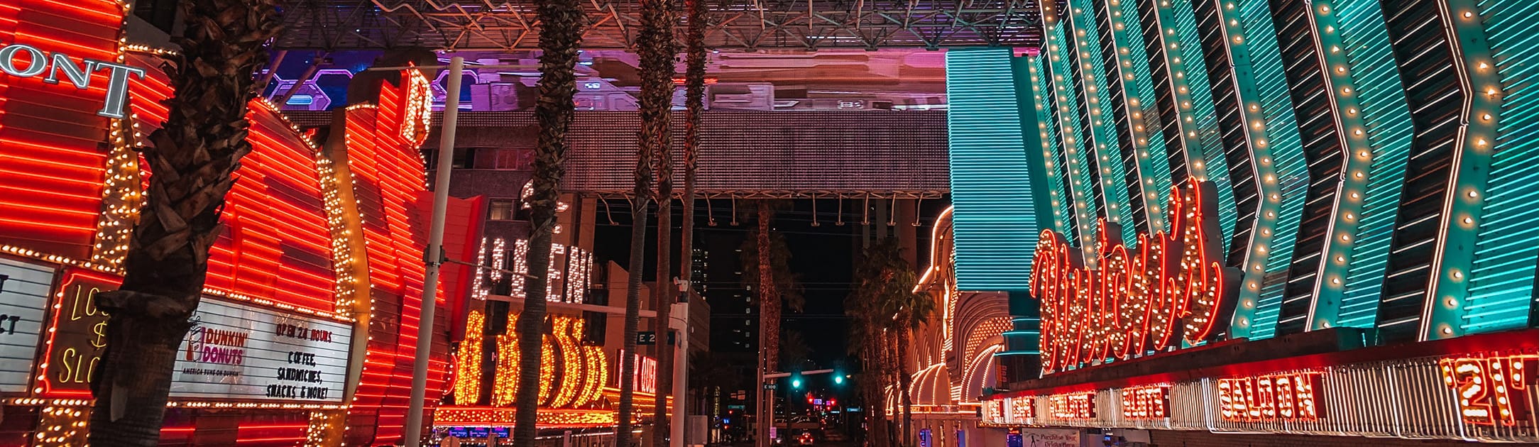 Center walking area with casinos, bright red and blue lights and signs on both sides.