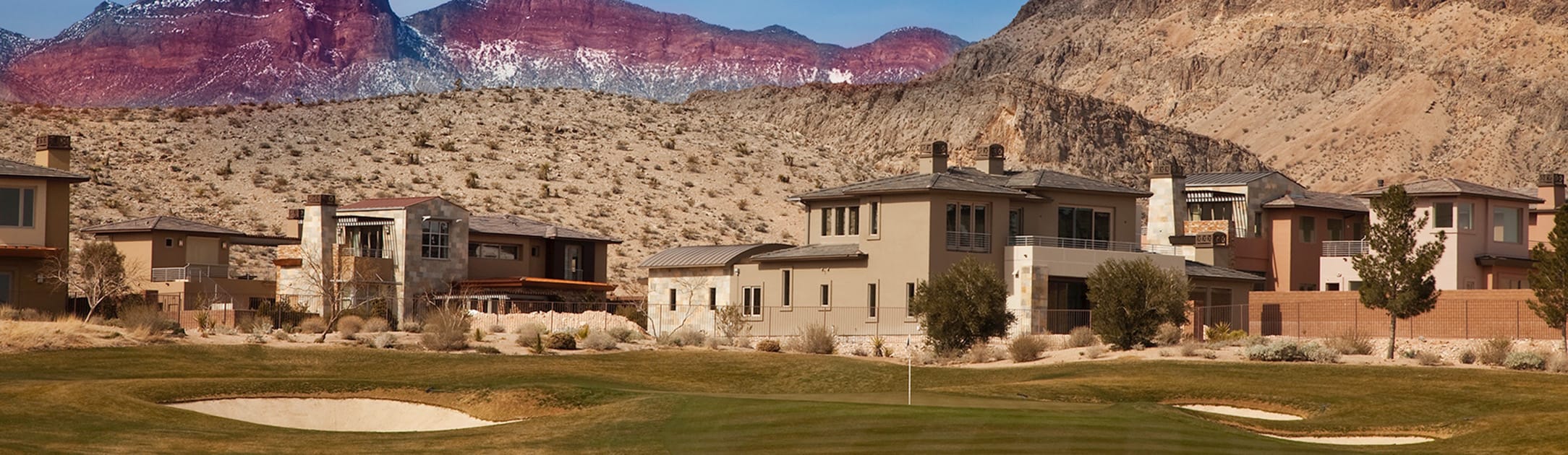 Golf course luxury homes with hills and red rock mountains in the background.
