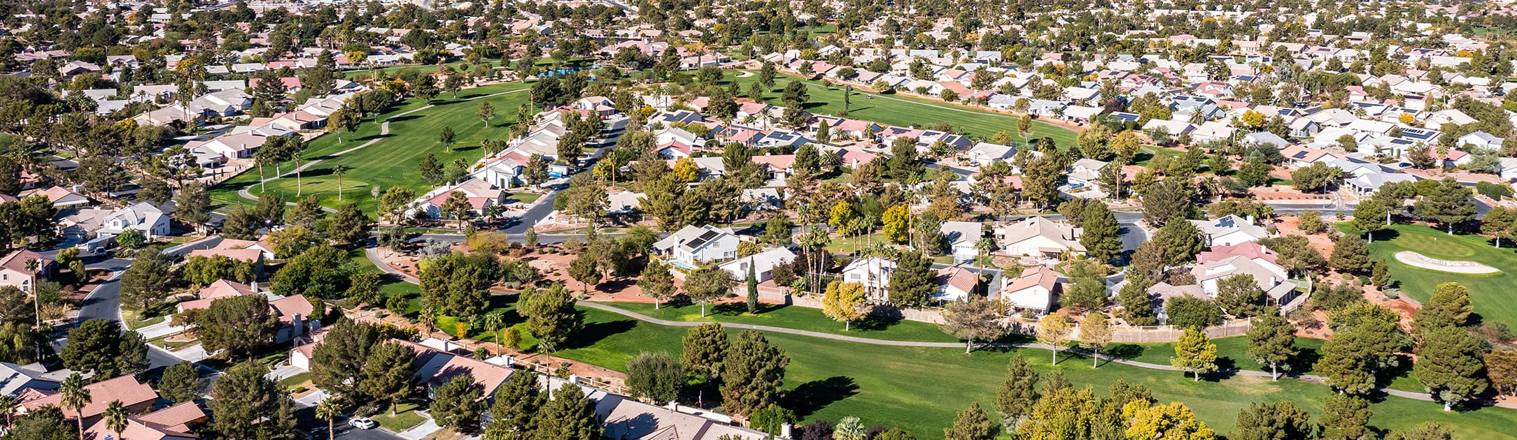 Aerial view of neighborhood with golf course surrounding luxury homes.