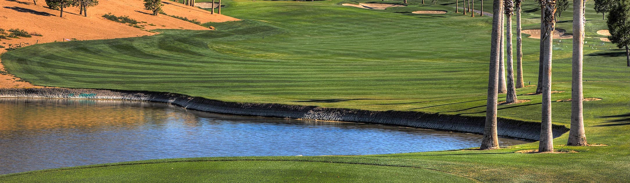 Golf course with water features and palm trees.