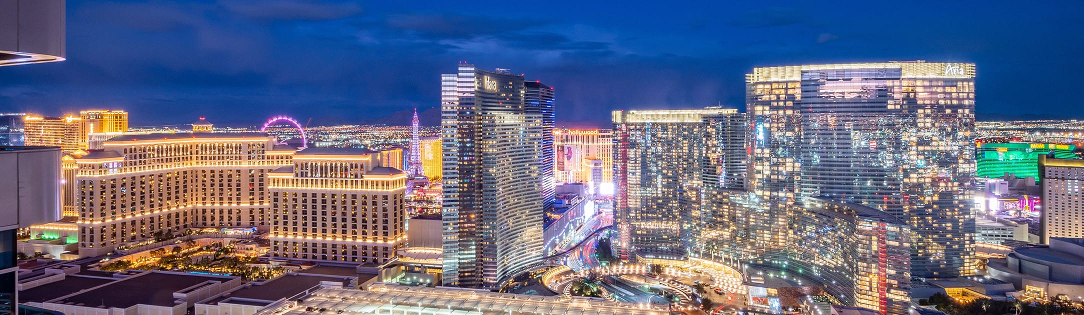 Night view of towers, high rises, casinos and mountains in the background.