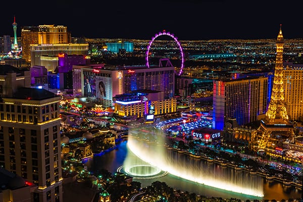 Las Vegas Strip at night, fountain, ferris wheel, htels, casinos and homes in the background.