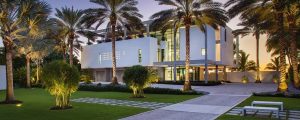 Modern white luxury home with grass and palm trees