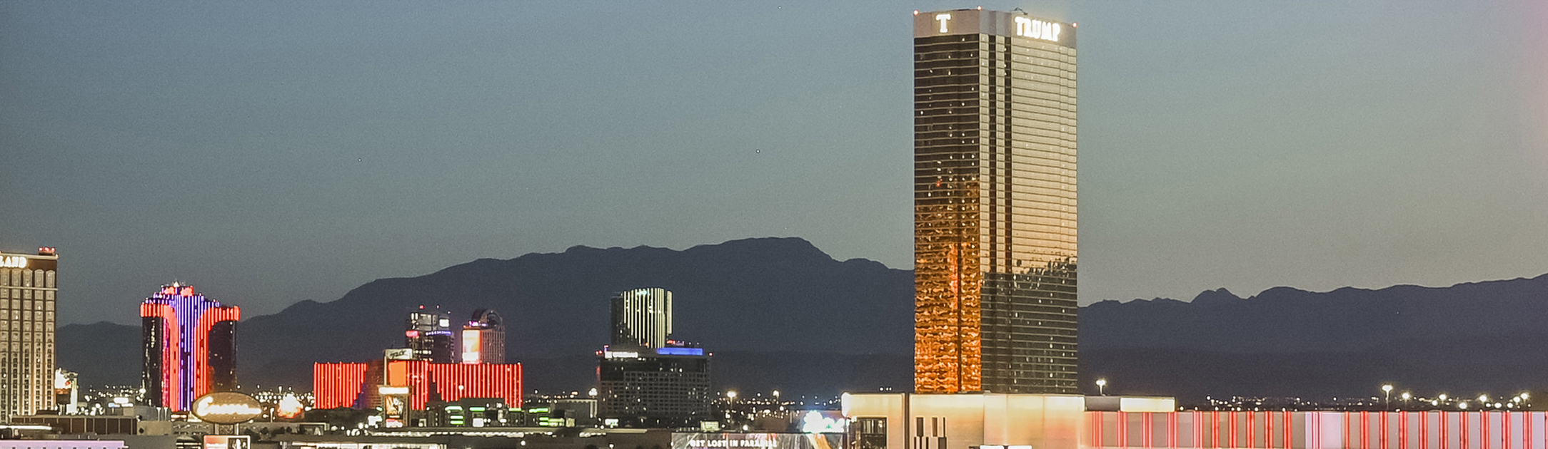 Gold high rise with a sign that says Trump with high rises and mountains in the background.