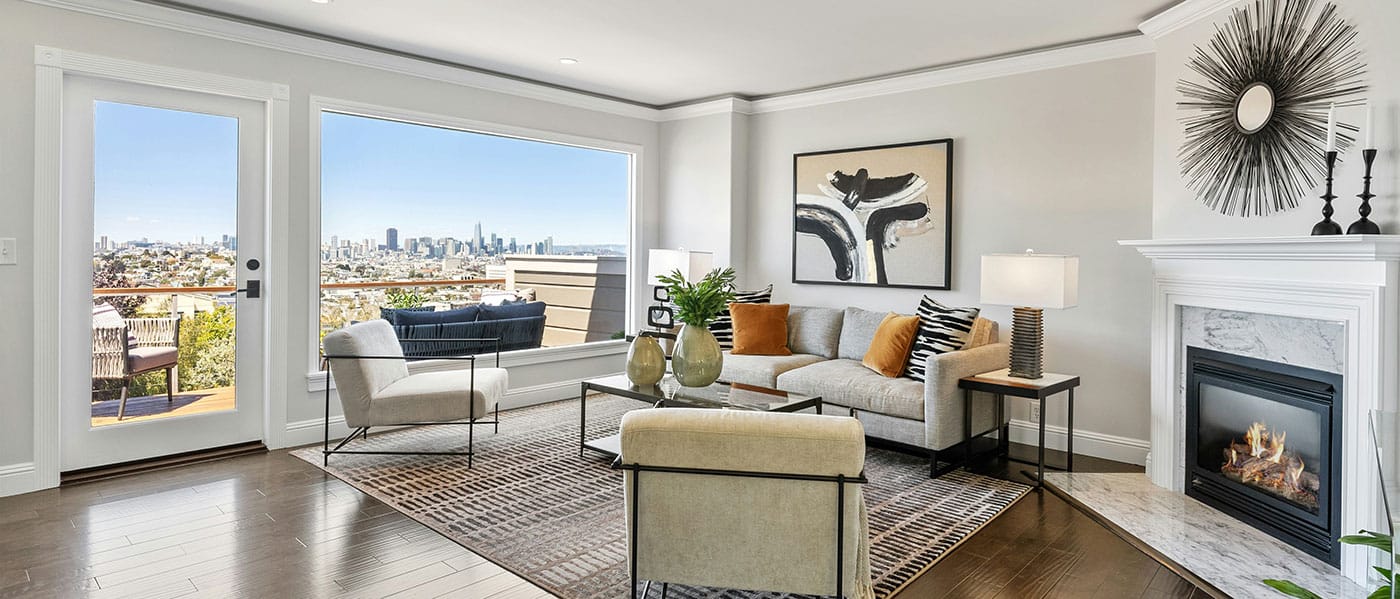 Daytime city views from penthouse with big windows, hardwood floors, fireplace, couch, chairs and rug